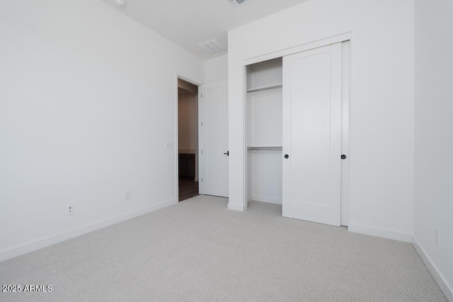 unfurnished bedroom with baseboards, visible vents, light carpet, and a closet