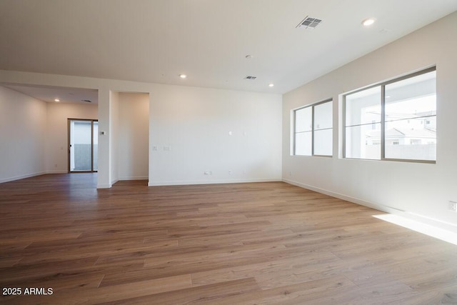 empty room with wood finished floors, visible vents, and recessed lighting