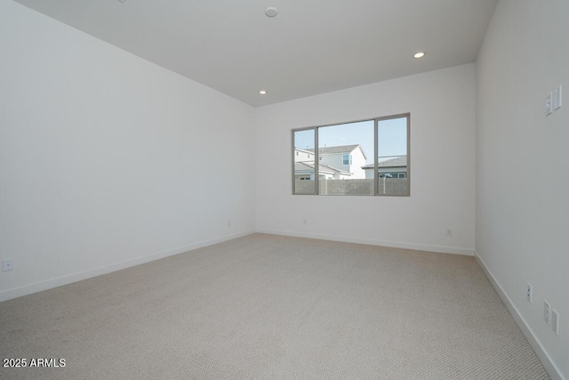 spare room with recessed lighting, light colored carpet, and baseboards