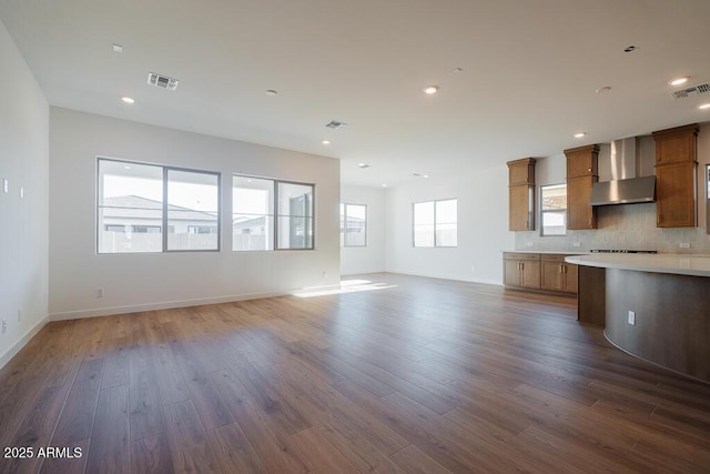 kitchen featuring visible vents, wall chimney exhaust hood, and open floor plan
