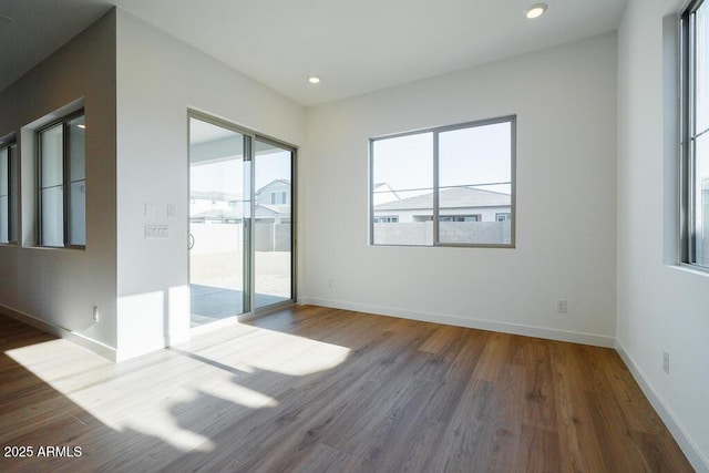 empty room with wood finished floors, recessed lighting, and baseboards