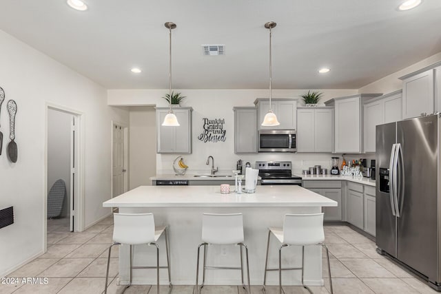 kitchen featuring sink, hanging light fixtures, stainless steel appliances, a breakfast bar area, and a center island with sink