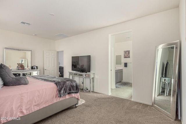 bedroom with ensuite bathroom and light colored carpet