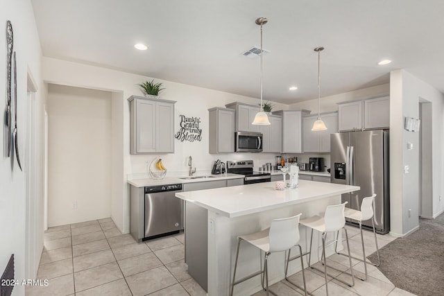 kitchen featuring sink, gray cabinets, a kitchen island, a kitchen bar, and stainless steel appliances