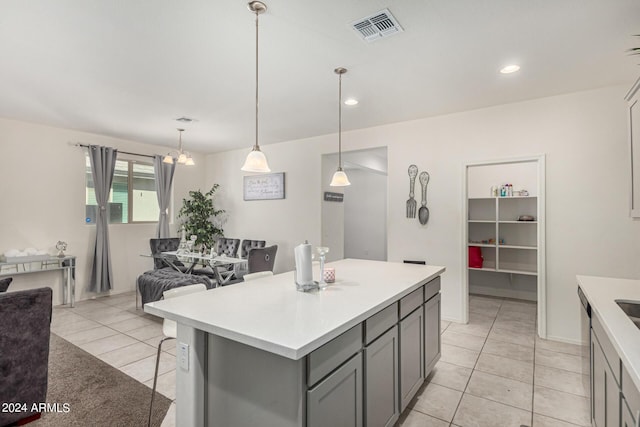 kitchen with light tile patterned floors, decorative light fixtures, gray cabinets, and a kitchen island