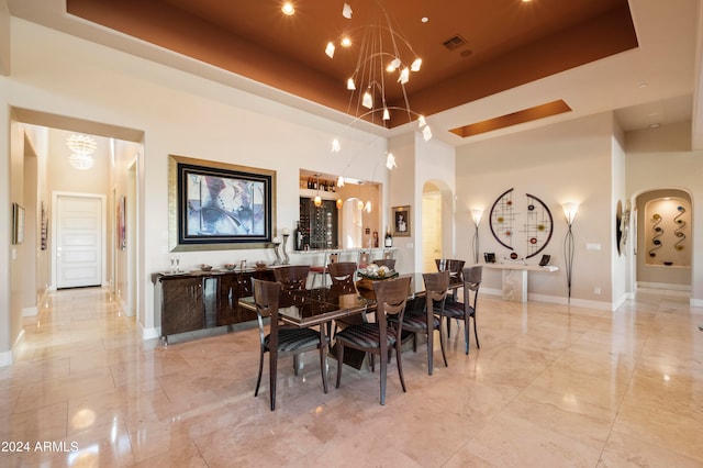 dining room with a tray ceiling, a notable chandelier, and a towering ceiling