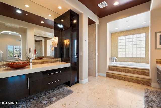 bathroom featuring vanity and a relaxing tiled tub