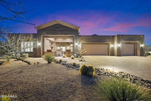 view of front facade featuring stucco siding, an attached garage, and decorative driveway