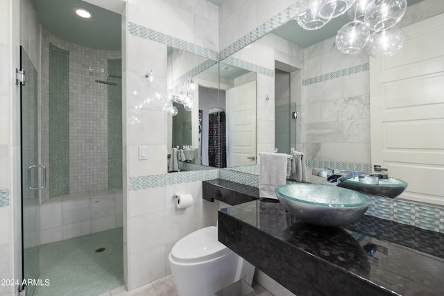 bathroom featuring toilet, a stall shower, tile walls, and a sink