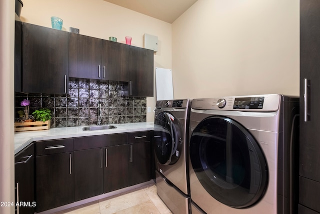 laundry area with light tile patterned floors, cabinets, washing machine and clothes dryer, and sink