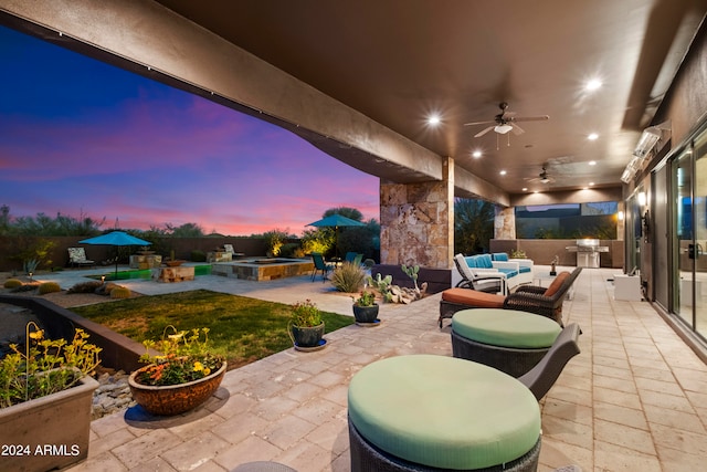 patio terrace at dusk featuring an outdoor living space, ceiling fan, and a pool with hot tub