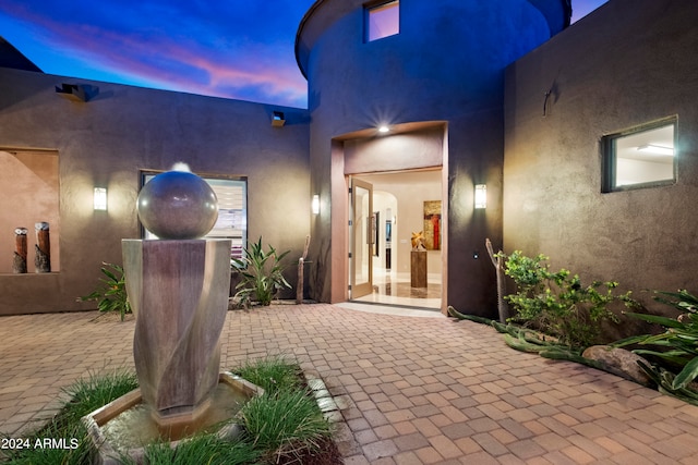 exterior entry at dusk featuring a patio