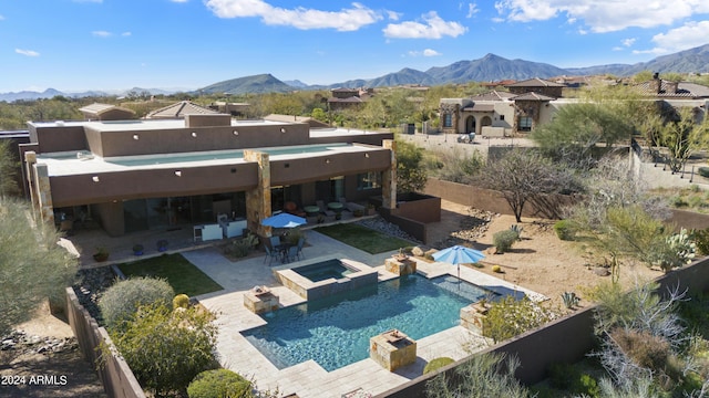 rear view of house featuring a mountain view, a patio area, a fenced backyard, and a pool with connected hot tub