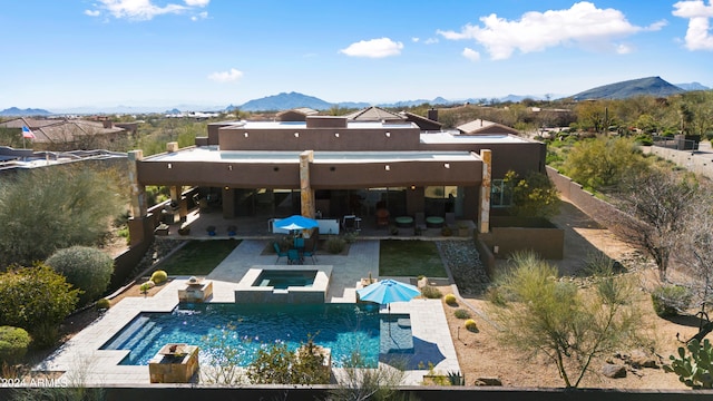 back of house with a mountain view, a patio, and a swimming pool with hot tub