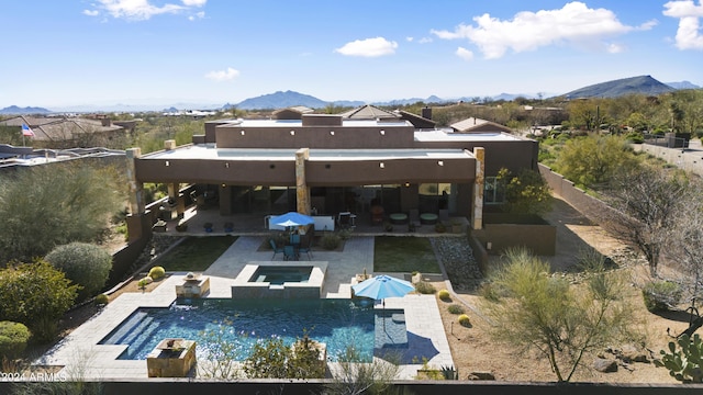 rear view of house with a mountain view, a pool with connected hot tub, a fenced backyard, and a patio area