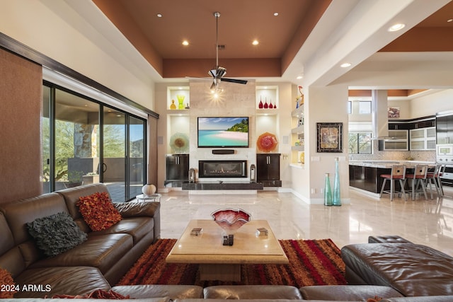 living room with baseboards, a tray ceiling, recessed lighting, a fireplace, and marble finish floor