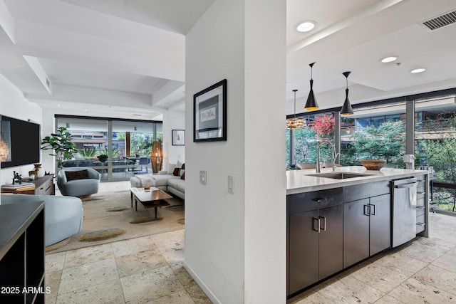 kitchen with visible vents, dishwasher, open floor plan, light countertops, and a sink