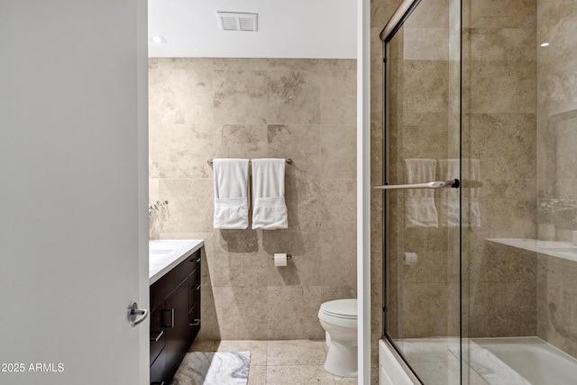 full bathroom featuring vanity, visible vents, tile walls, and a shower with shower door