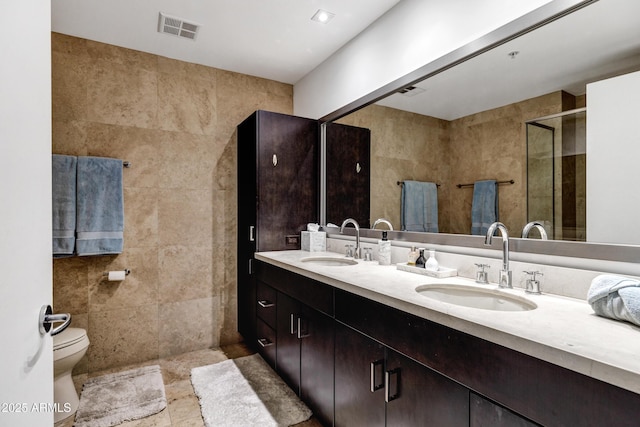 bathroom with tile walls, a shower stall, visible vents, and a sink