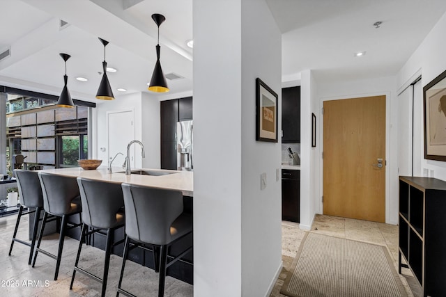 kitchen with pendant lighting, visible vents, a sink, stainless steel fridge, and a kitchen breakfast bar