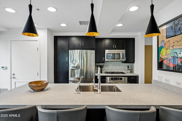 kitchen with a breakfast bar area, visible vents, appliances with stainless steel finishes, a sink, and dark cabinets