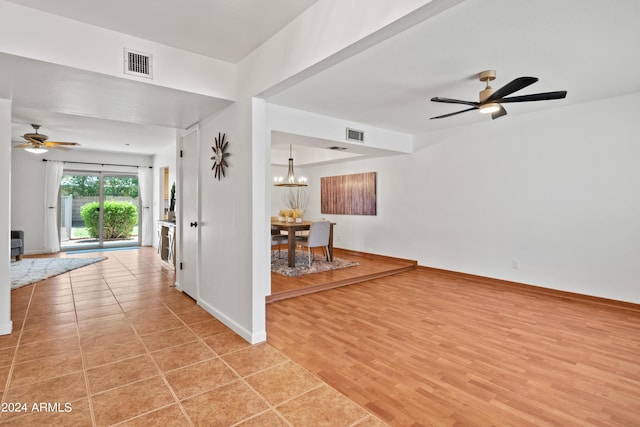 spare room featuring ceiling fan with notable chandelier and light hardwood / wood-style flooring