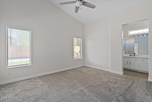 unfurnished bedroom with ceiling fan, light colored carpet, ensuite bathroom, sink, and high vaulted ceiling