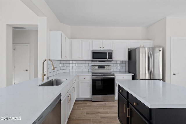 kitchen featuring decorative backsplash, white cabinetry, appliances with stainless steel finishes, and sink