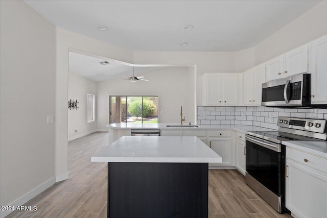 kitchen with tasteful backsplash, sink, a kitchen island, appliances with stainless steel finishes, and light hardwood / wood-style flooring