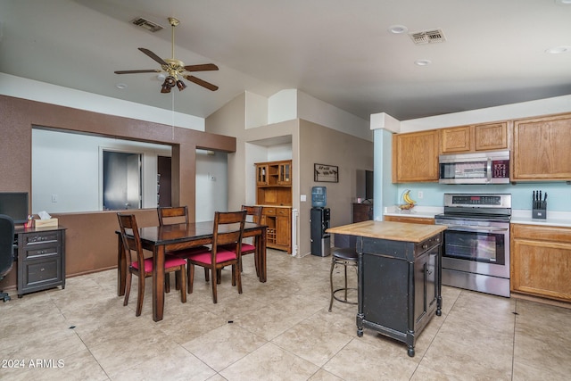 kitchen with appliances with stainless steel finishes, vaulted ceiling, a center island, butcher block countertops, and a breakfast bar area