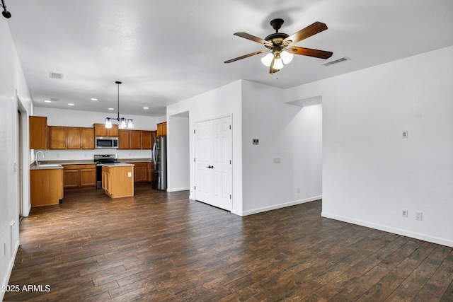 kitchen with dark hardwood / wood-style flooring, appliances with stainless steel finishes, decorative light fixtures, and a center island