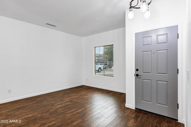 foyer entrance with dark wood-type flooring and an inviting chandelier