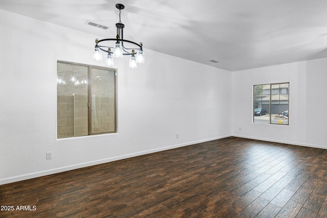 empty room featuring an inviting chandelier and dark hardwood / wood-style floors