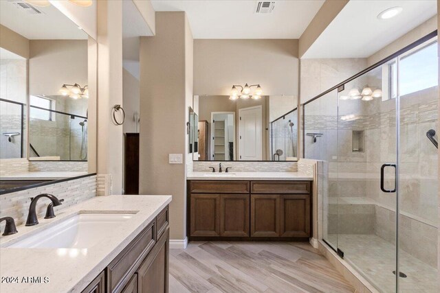 bathroom featuring wood-type flooring, an enclosed shower, vanity, and tasteful backsplash