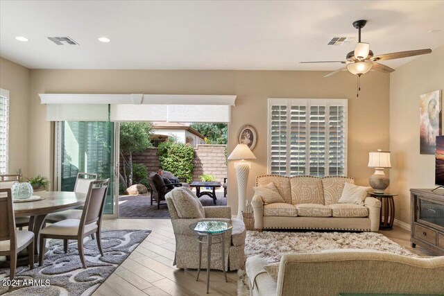 living room with ceiling fan and light hardwood / wood-style flooring