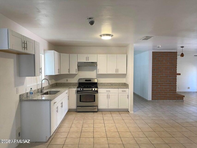 kitchen with gas range, light tile patterned floors, white cabinetry, and sink