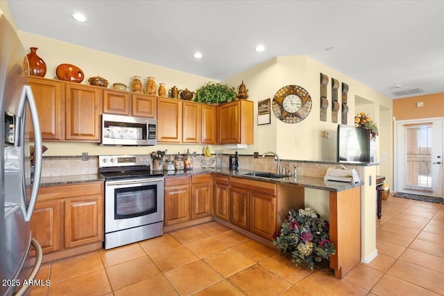 kitchen featuring sink, stainless steel appliances, kitchen peninsula, dark stone countertops, and light tile patterned floors