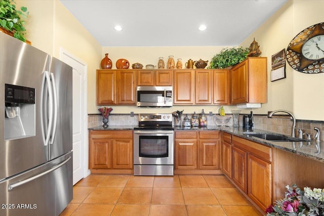 kitchen with light tile patterned flooring, sink, appliances with stainless steel finishes, and dark stone counters