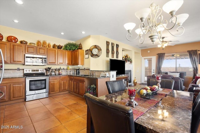 kitchen with appliances with stainless steel finishes, ceiling fan with notable chandelier, sink, decorative light fixtures, and light tile patterned flooring