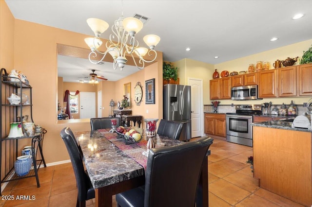 tiled dining area featuring ceiling fan with notable chandelier and sink