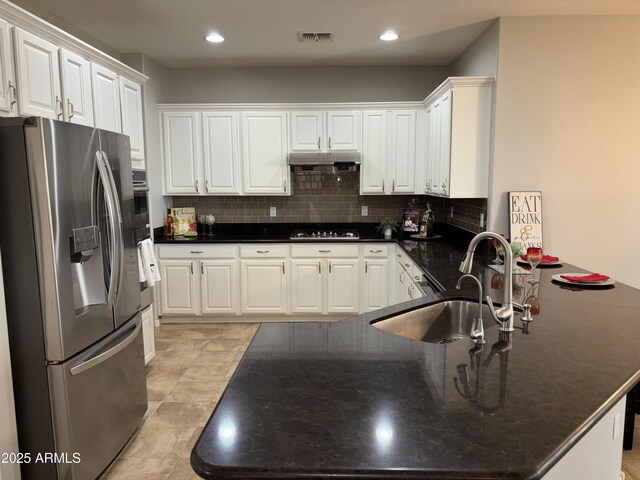 kitchen with appliances with stainless steel finishes, white cabinets, backsplash, and light tile patterned floors