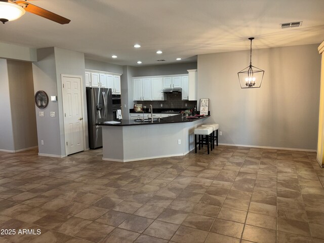 kitchen with decorative light fixtures, tasteful backsplash, wall chimney exhaust hood, sink, and light tile patterned floors