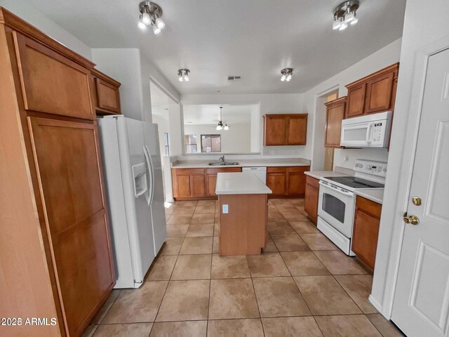 5339 W Maldonado Rd, Laveen, AZ 85339 - kitchen with white appliances, brown cabinetry, a center island, light countertops, and light tile patterned floors