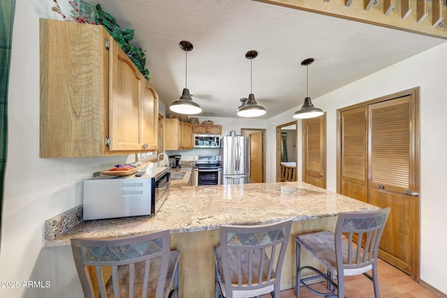 17425 Sequoia Dr, Munds Park, AZ 86017 - kitchen with stainless steel appliances, a peninsula, a kitchen bar, light stone countertops, and hanging light fixtures