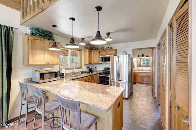 17425 Sequoia Dr, Munds Park, AZ 86017 - kitchen featuring appliances with stainless steel finishes, a peninsula, a sink, light stone countertops, and decorative light fixtures