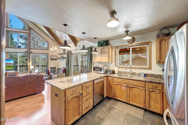 17425 Sequoia Dr, Munds Park, AZ 86017 - kitchen featuring appliances with stainless steel finishes, a sink, a peninsula, a textured ceiling, and light stone countertops