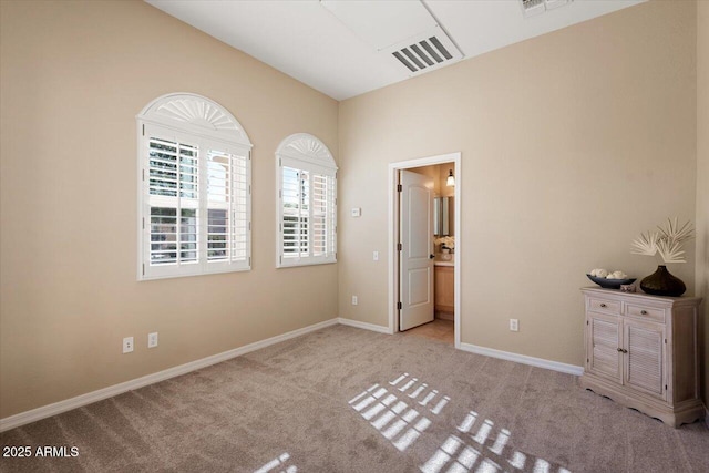 unfurnished bedroom with light colored carpet, lofted ceiling, and ensuite bathroom