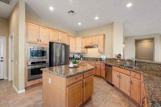 kitchen featuring stainless steel appliances, a center island, sink, and dark stone countertops