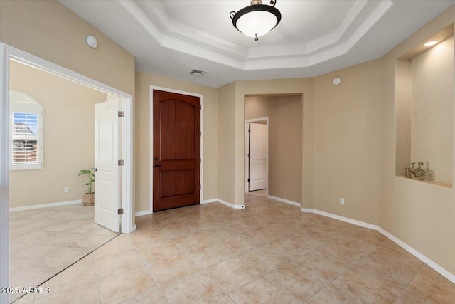 spare room with light tile patterned floors and a raised ceiling