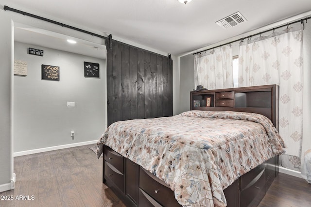 bedroom featuring a barn door and dark hardwood / wood-style flooring